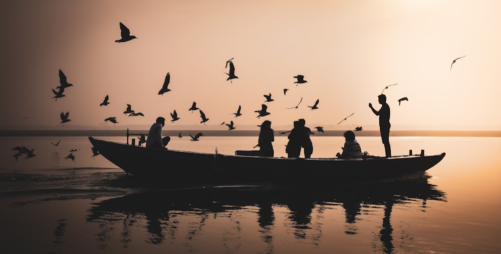 silhouette of people riding on boat during sunset