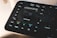 A close-up view of a Loupedeck editing console, featuring various labeled buttons and a central control dial. Buttons include functions such as undo, redo, shift, control, and others related to editing tasks. The interface appears sleek and designed for efficient workflow management.