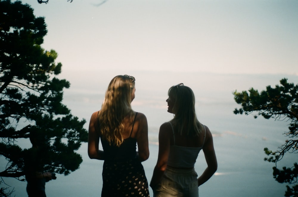 2 women in black and white polka dots dress standing near green trees during daytime