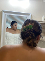 A woman applying a floral western fragrance in front of a mirror framed with bright Mexican green and red accents.