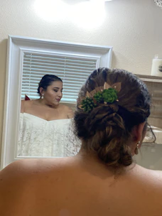 A woman applying a floral western fragrance in front of a mirror framed with bright Mexican green and red accents.