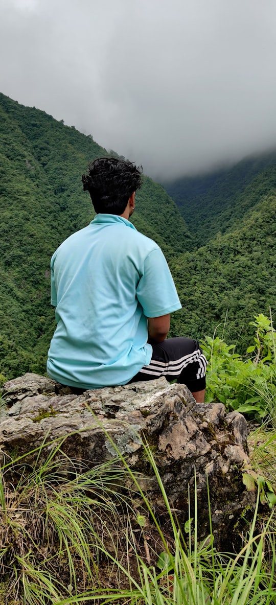 man in white t-shirt sitting on rock during daytime in Lalitpur Nepal