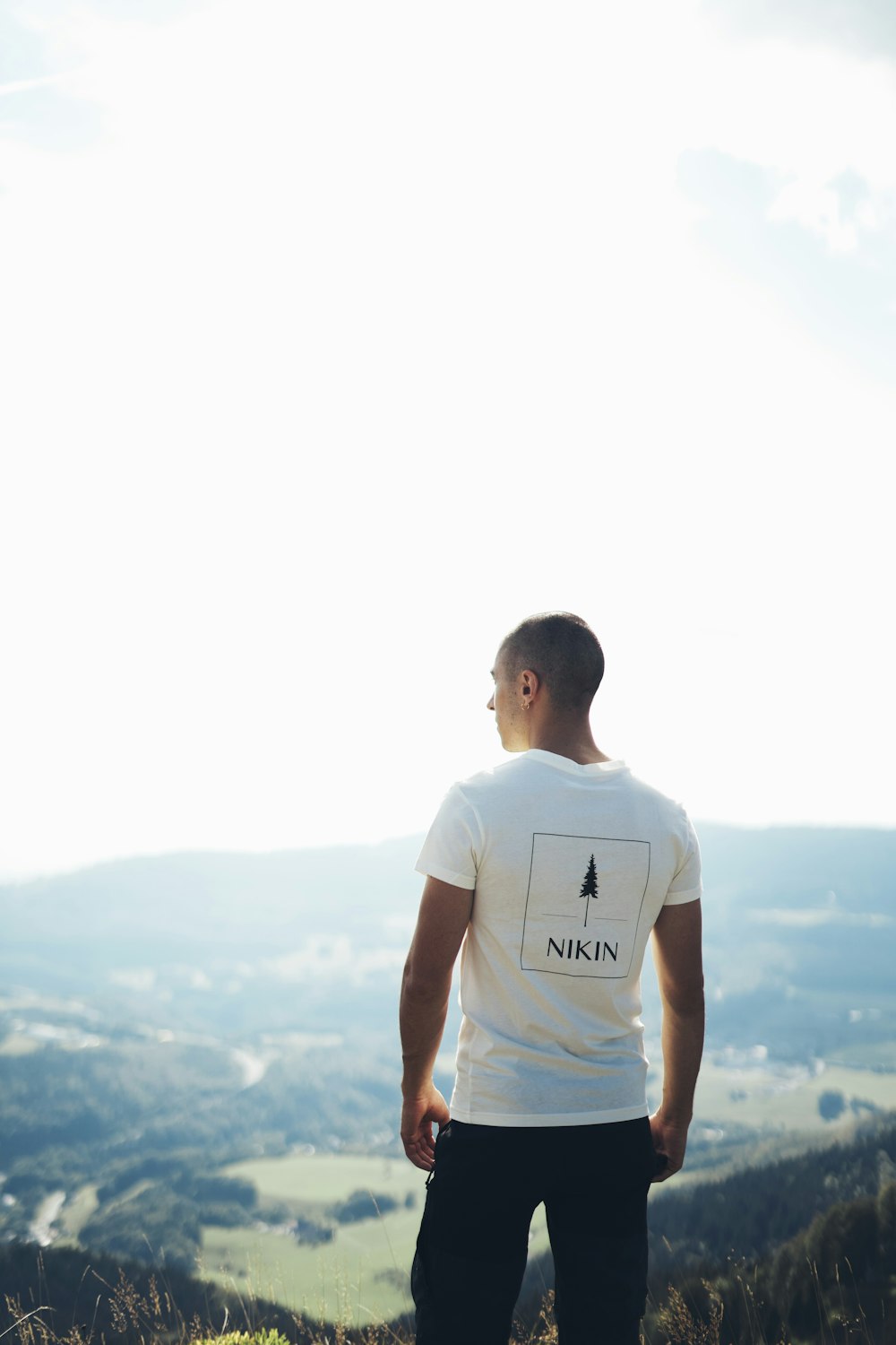 man in white crew neck t-shirt standing on top of mountain during daytime