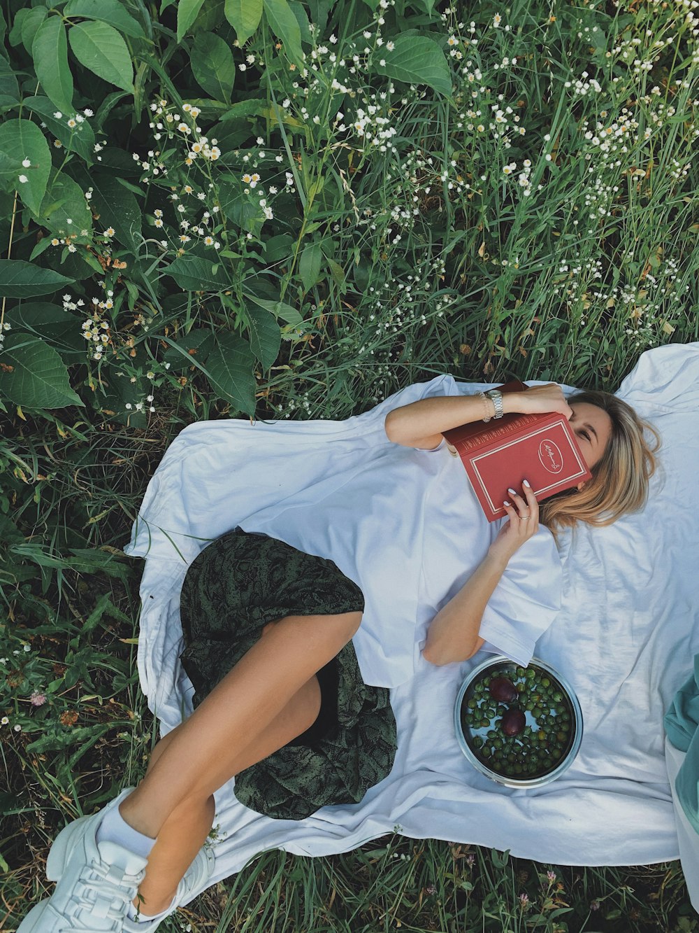 woman in white t-shirt lying on green grass field