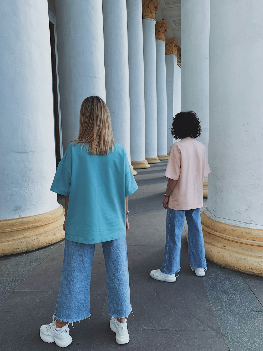 2 women standing in front of white wall