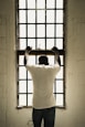 man in white t-shirt standing in front of window