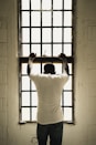 man in white t-shirt standing in front of window