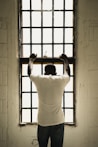 man in white t-shirt standing in front of window