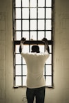 man in white t-shirt standing in front of window