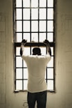 man in white t-shirt standing in front of window