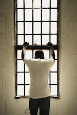 man in white t-shirt standing in front of window