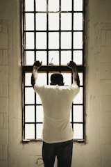 man in white t-shirt standing in front of window