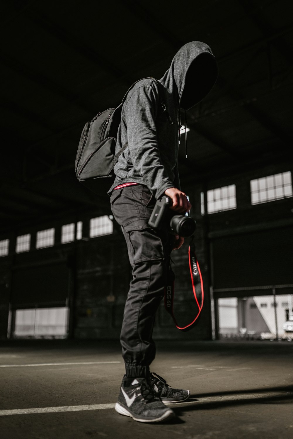 Uomo in giacca di pelle nera e jeans in denim nero che tiene una fotocamera DSLR nera