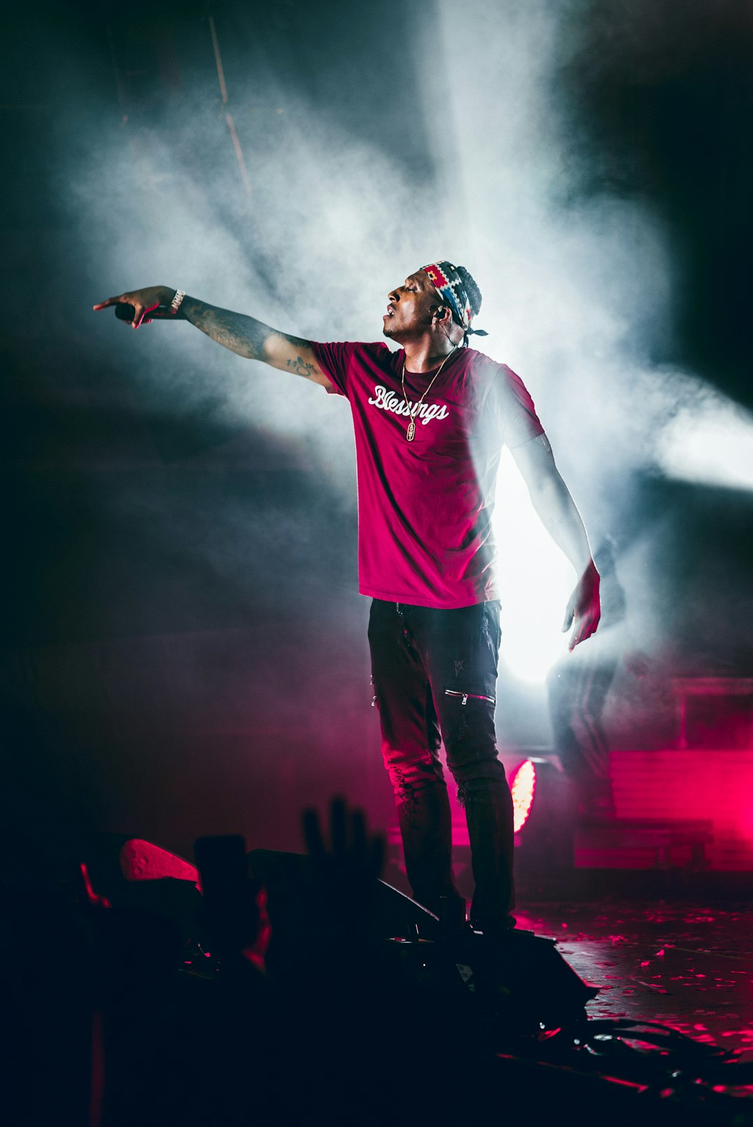 man in red crew neck t-shirt and blue denim jeans standing on stage