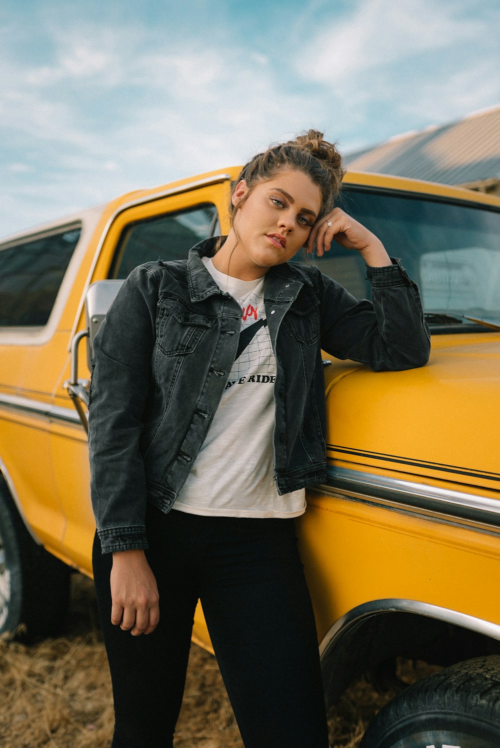 Mujer en blazer negro de pie junto a un coche amarillo