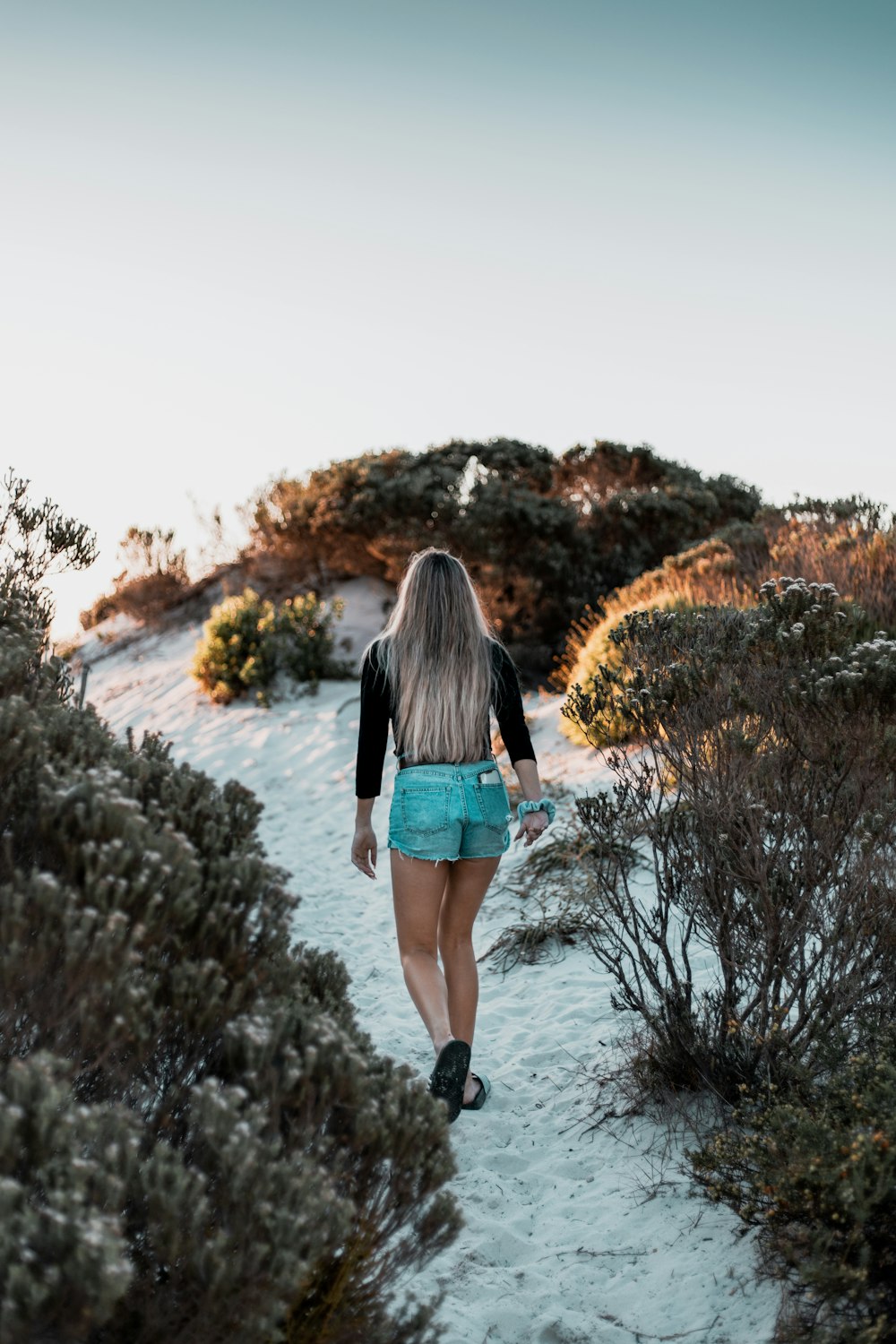 woman in black long sleeve shirt and blue denim shorts standing on brown grass field during
