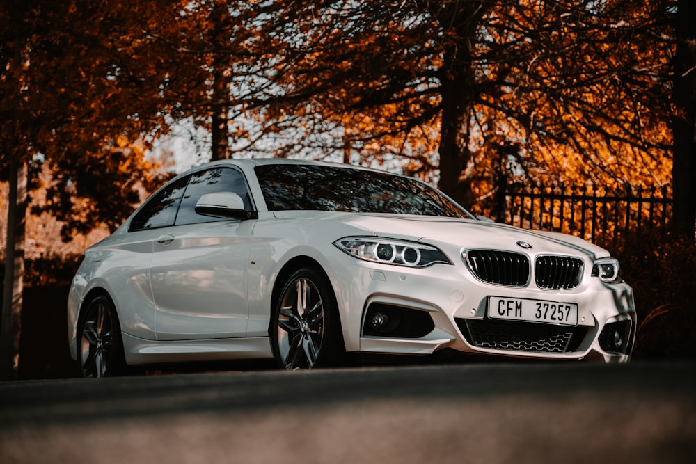 BMW M 3 coupé blanco estacionado cerca de árboles marrones durante el día