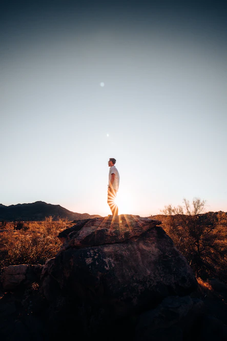 man in white long sleeve shirt standing on brown rock during daytime