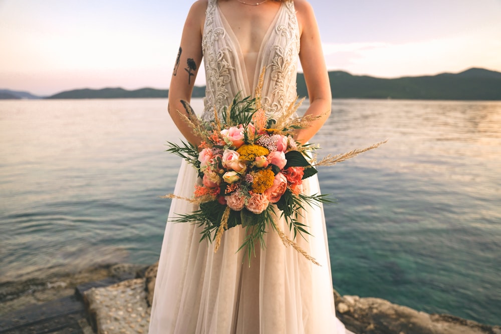 Frau in weißem ärmellosem Kleid mit Blumenstrauß