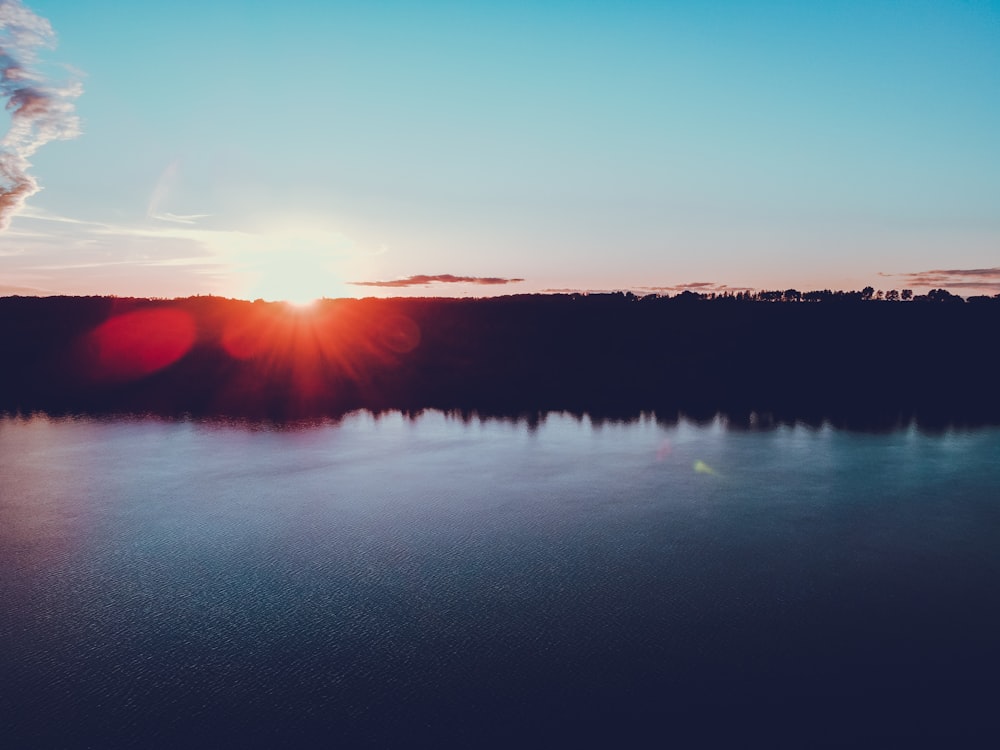 日没時の木々の近くの水域