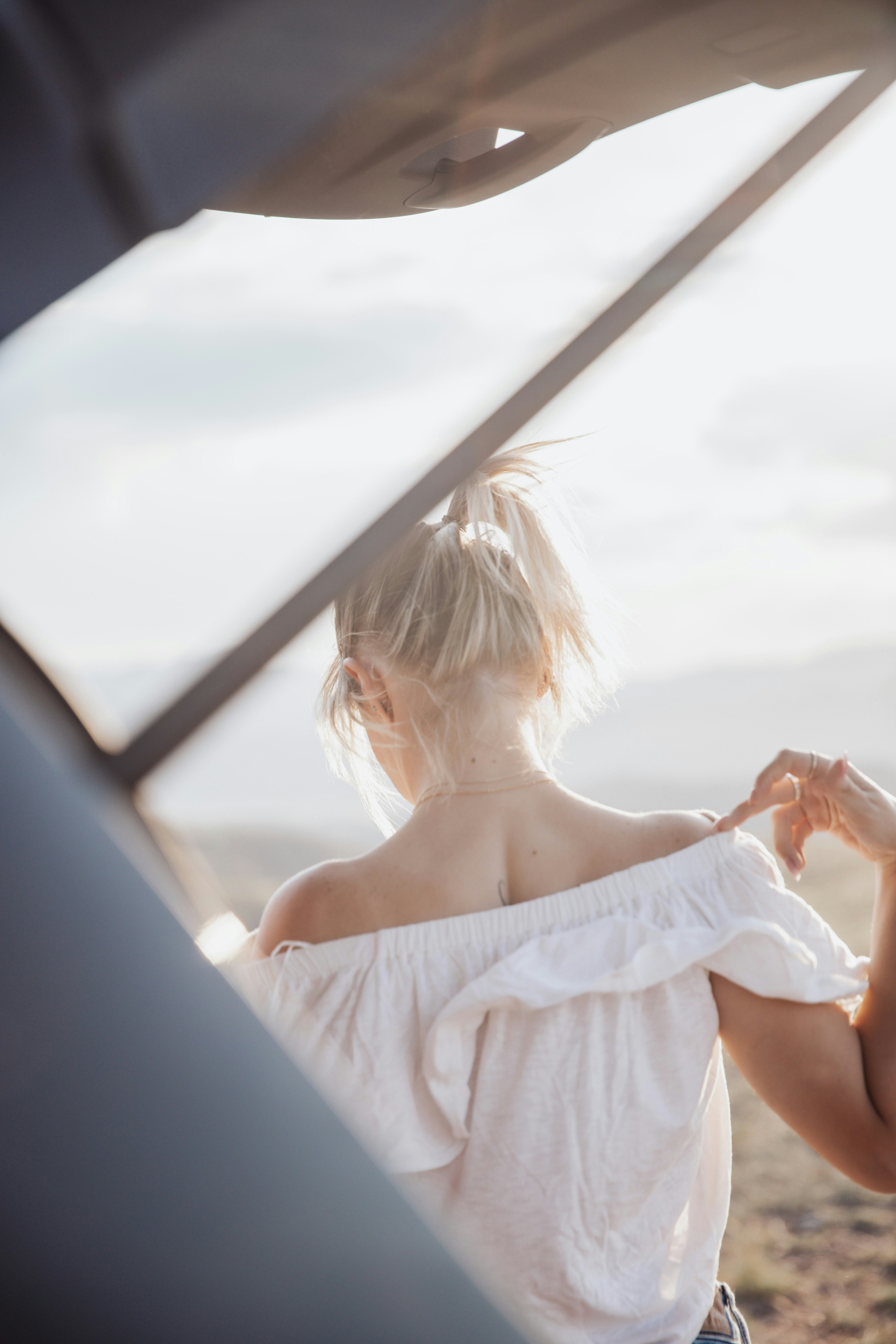 woman in white tube dress sitting on car seat during daytime