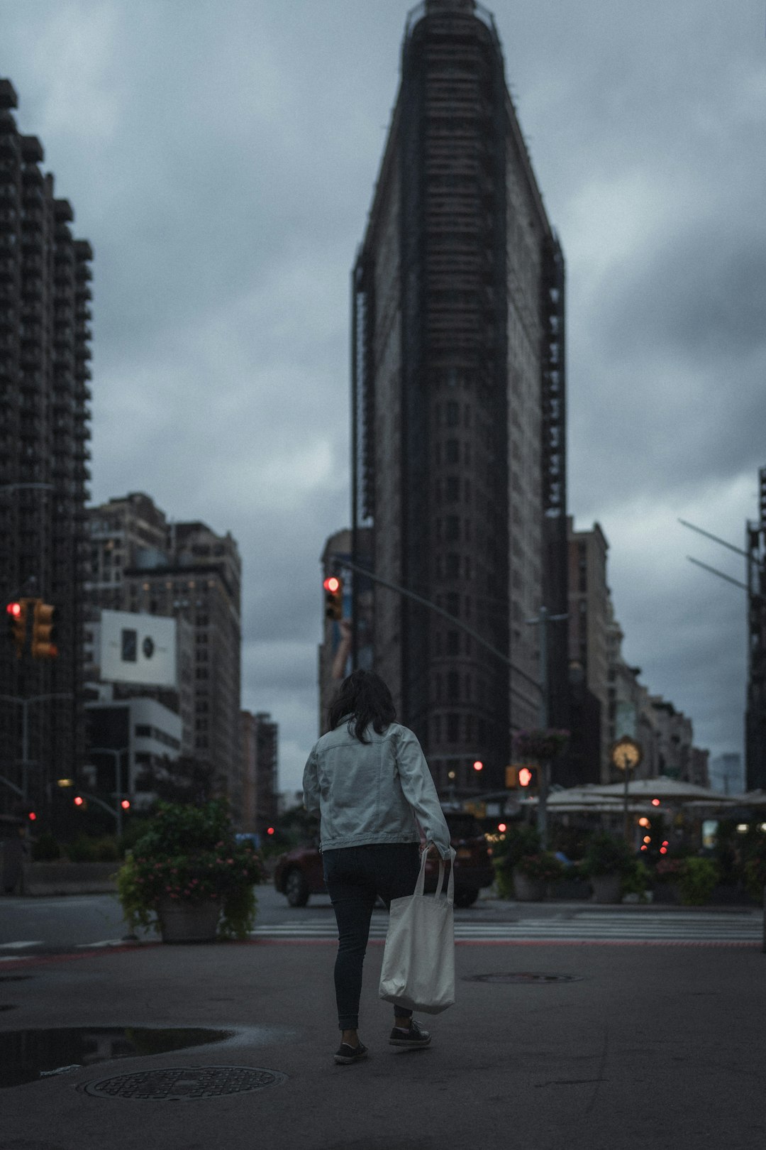 woman in gray jacket standing on gray asphalt road during daytime