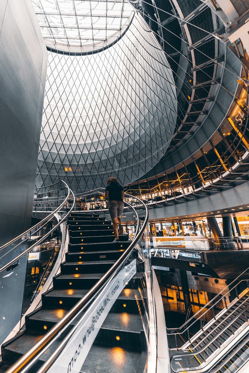 man in black jacket and blue denim jeans standing on escalator