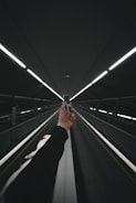 person in black pants walking on escalator