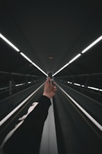 person in black pants walking on escalator