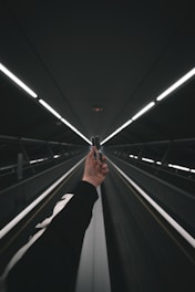 person in black pants walking on escalator
