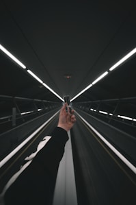 person in black pants walking on escalator