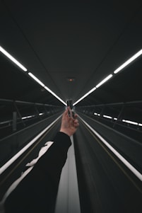person in black pants walking on escalator