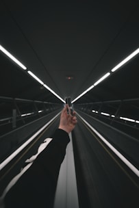 person in black pants walking on escalator