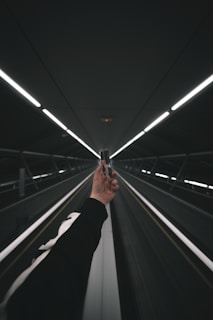 person in black pants walking on escalator