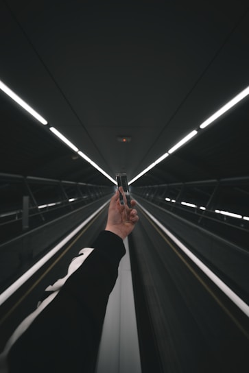 person in black pants walking on escalator