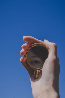 Artistic shot of a gold compact mirror reflecting a blue sky