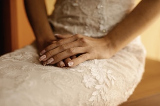 A close-up of elegantly manicured hands resting on a soft fabric.