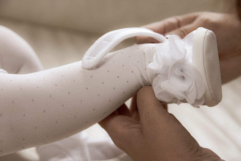 person holding white textile with white ribbon