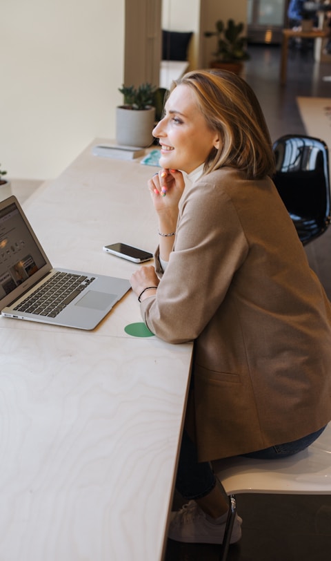 woman in brown coat using macbook air