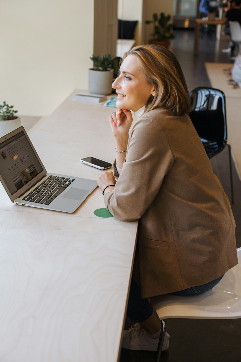 Frau im braunen Mantel mit MacBook Air