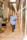 woman in blue dress shirt and blue denim jeans standing beside brown wooden chair