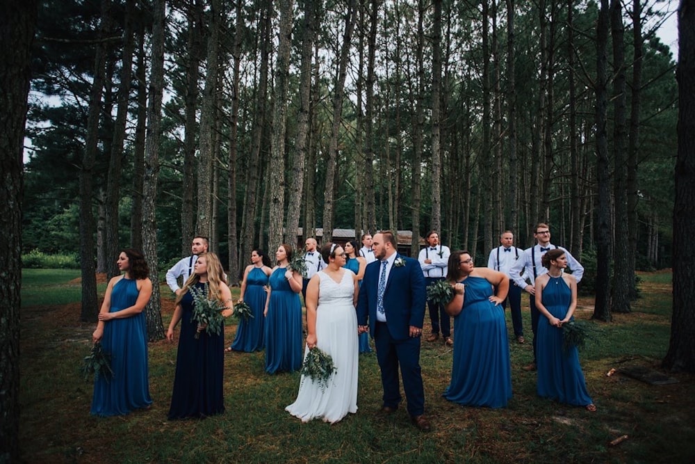 pessoas em vestidos azuis e brancos em pé no campo de grama verde cercado por árvores verdes durante