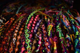 Hands weaving a vibrant friendship bracelet with colorful threads.