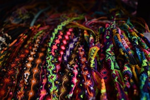 A colorful display of handmade friendship bracelets laid out on a wooden table.