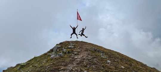 person jumping on rocky mountain under cloudy sky during daytime in Davos Switzerland