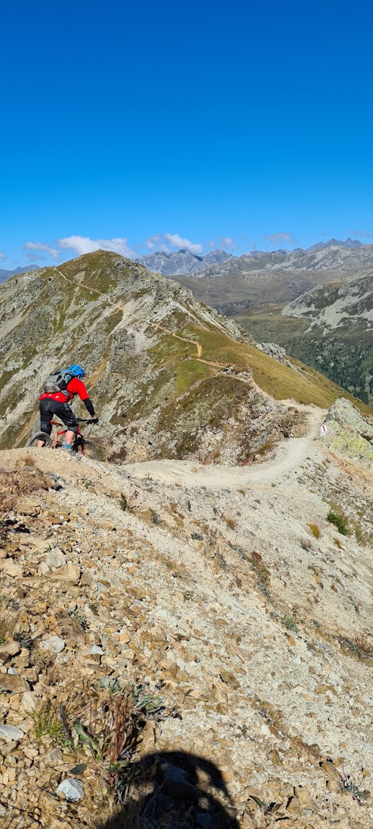 man in black jacket and black pants riding bicycle on mountain during daytime in Davos Switzerland