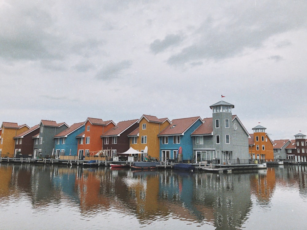 houses beside body of water under cloudy sky during daytime