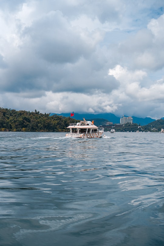 white boat on sea under cloudy sky during daytime in Sun Moon Lake Taiwan