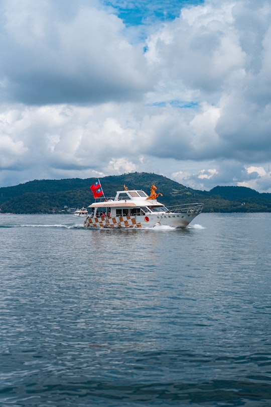 white boat on sea under cloudy sky during daytime in Sun Moon Lake Taiwan