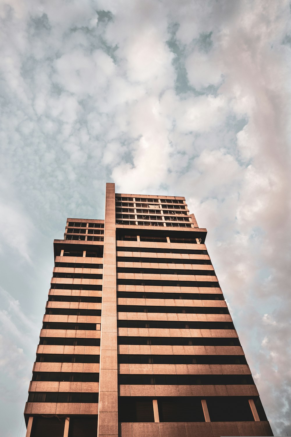 Edificio de hormigón marrón bajo nubes blancas durante el día